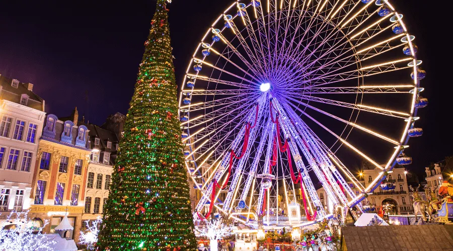 Christmas market chalets lit at night with visitors walking between them