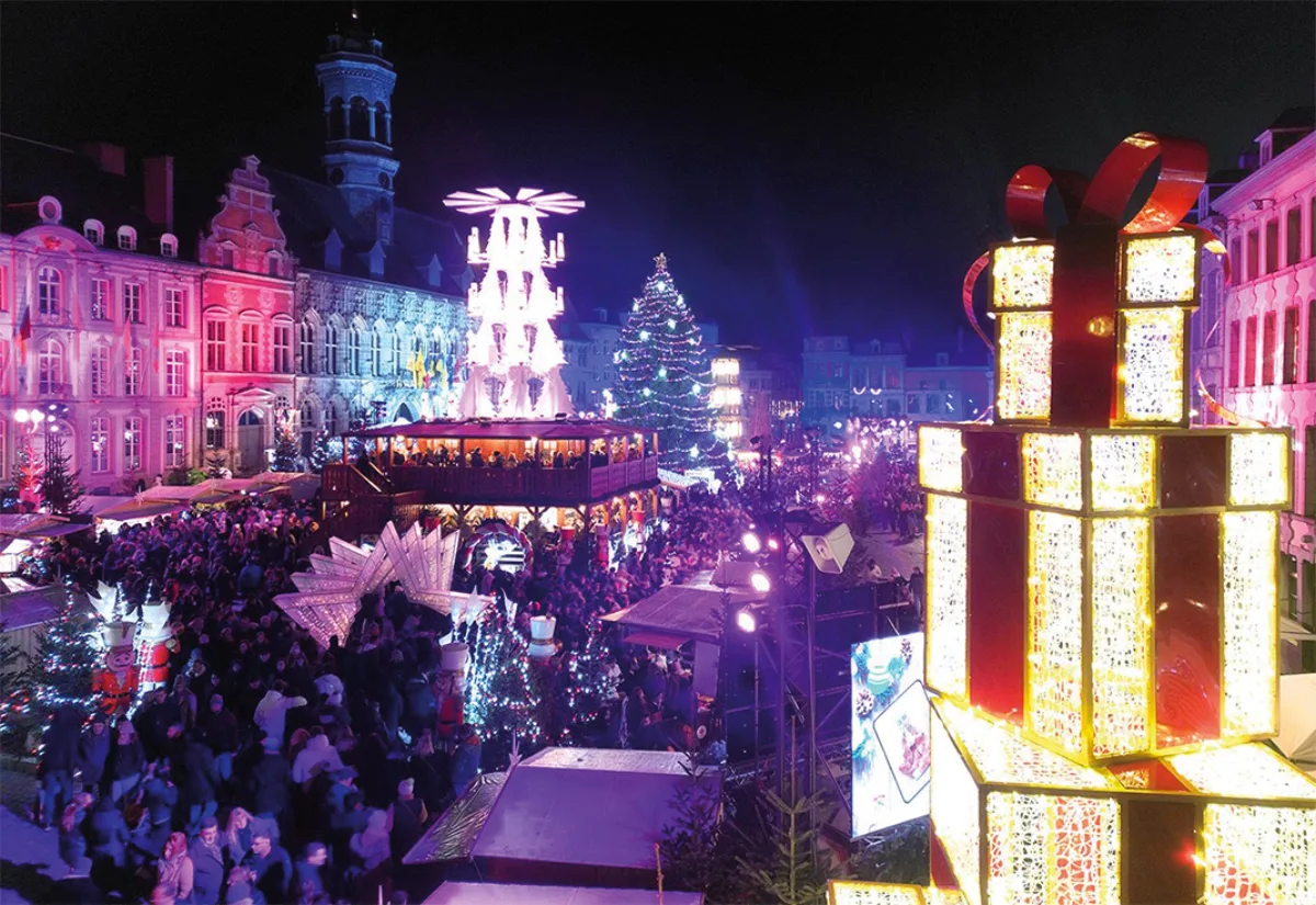 Christmas market on the Grand-Place in Mons at night, crowd, lit pyramid and giant illuminated gift boxes