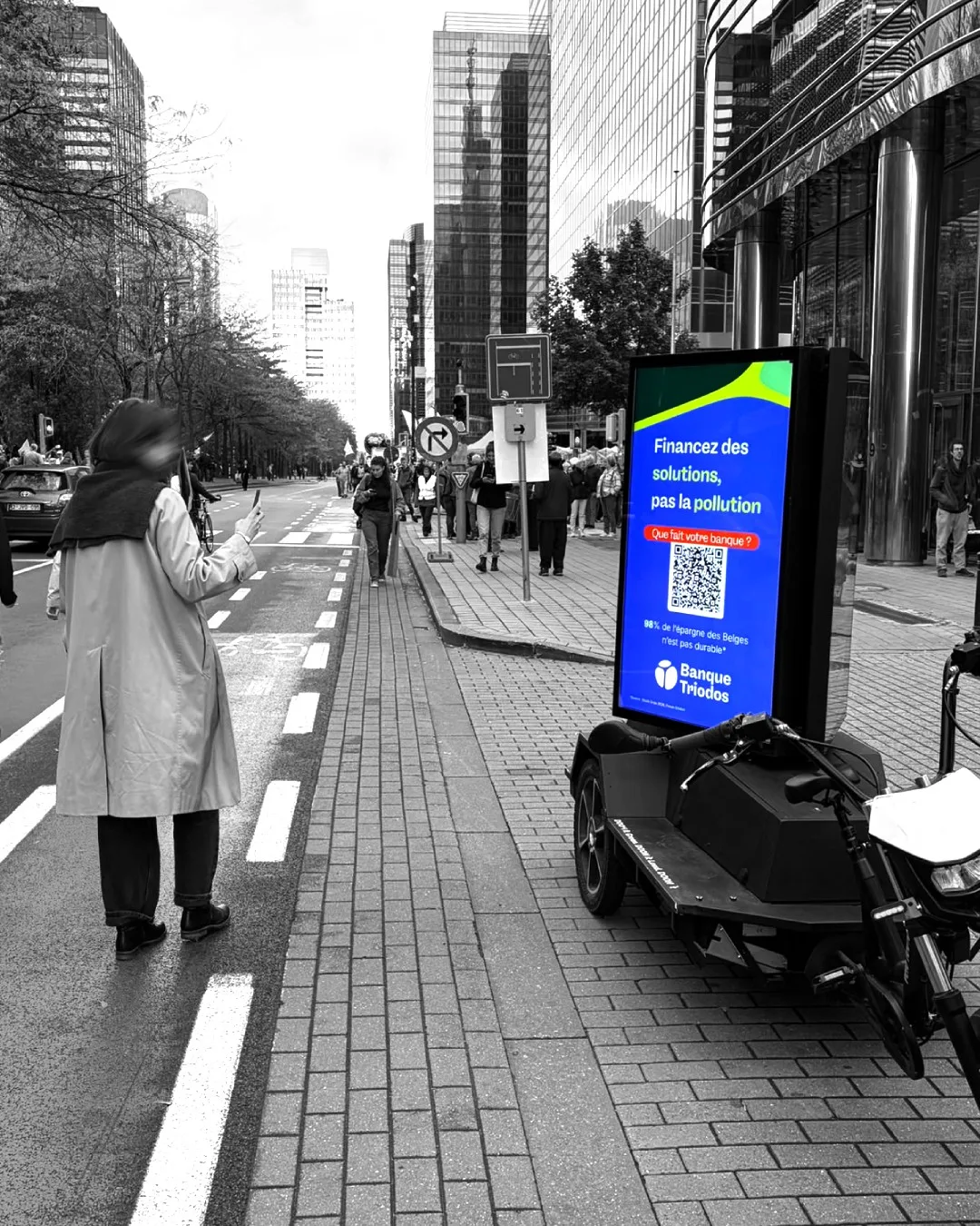 Écran LED Triodos sur un vélo cargo électrique à la Marche pour le Climat à Bruxelles : « Financez des solutions, pas la pollution », avec le QR code « Que fait votre banque ? »